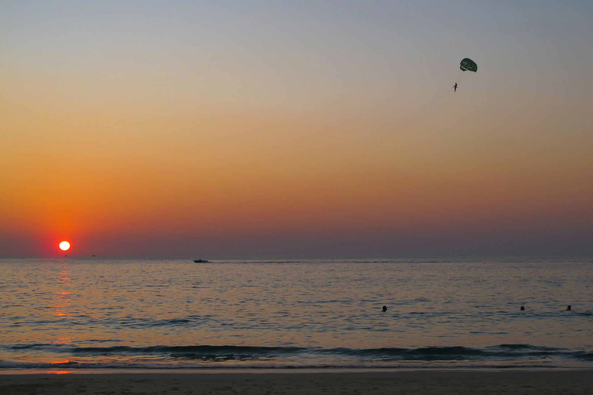 Parasailing over the sea at sunset at Karon Beach